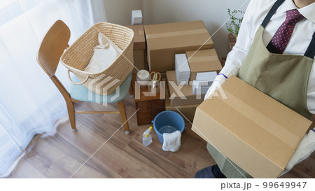 引越しの荷造り・荷解きをするスーツにエプロン姿の男性 仕事や転勤の引越しイメージ 引越しの荷造り・荷解きをするスーツにエプロン姿の男性 仕事や転勤の引越しイメージ 99649947