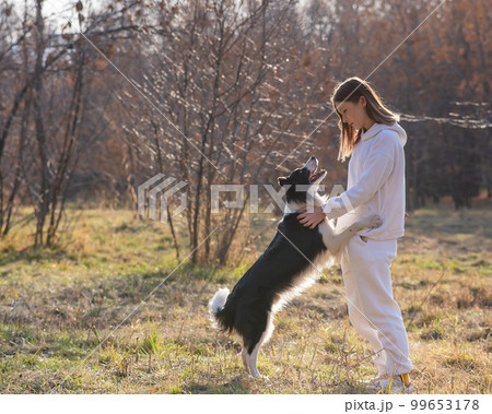 Caucasian woman hugging her dog Border Collie while sitting on a bench in autumn park. Caucasian woman hugging her dog Border Collie while sitting on a bench in autumn park. 99653178