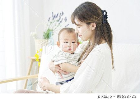 家で昼寝をする赤ちゃんを抱っこする母親 99653725