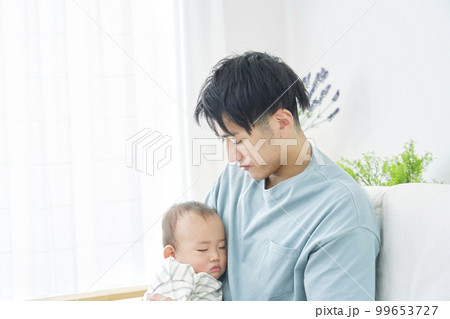 家で昼寝をする赤ちゃんを抱っこする父親 99653727