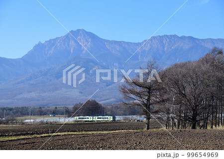 八ヶ岳を背景に晩秋の野辺山高原を走る小海線のローカル列車 99654969
