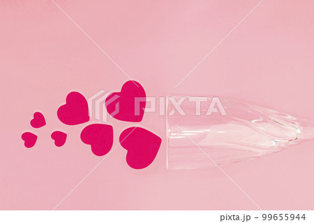 Pink hearts fall out of a glass goblet that lies on a pink background. ?oncept romantic composition for Valentine's day. Copy space. Top view 99655944