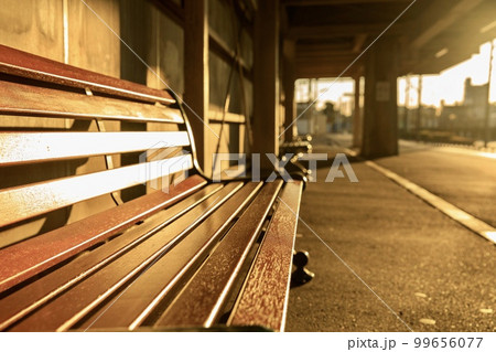 オレンジ色の陽に染まる駅のベンチ 99656077