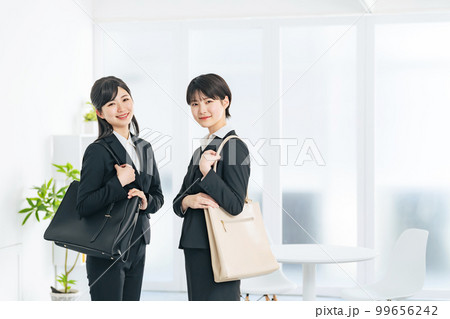 おしゃれなオフィスに立つスーツを着た二人の若い女性　就活生　フレッシャーズ 99656242