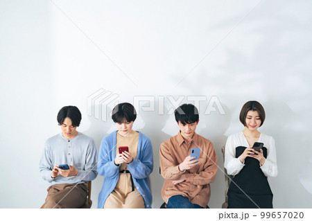 並んでスマホを見る若い4人グループ 99657020