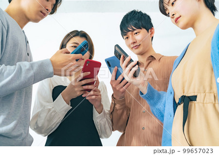 スマホを見せ合う若いグループ 99657023