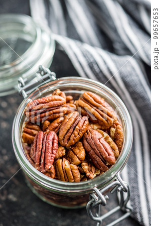Peeled pecan nuts in jar on kitchen table. Peeled pecan nuts in jar on kitchen table. 99657653
