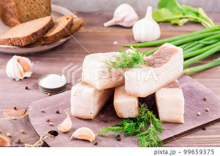 Salted lard with garlic and dill on a cutting board on a wooden table 99659375