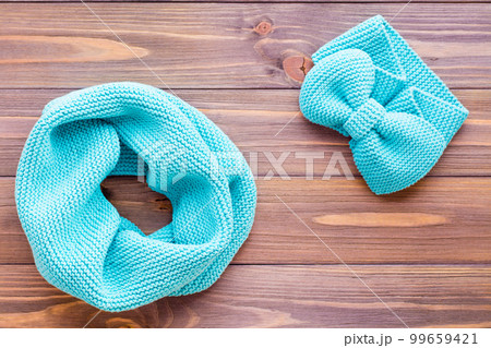 Knitted mint snud and headband on a wooden background. Top view 99659421