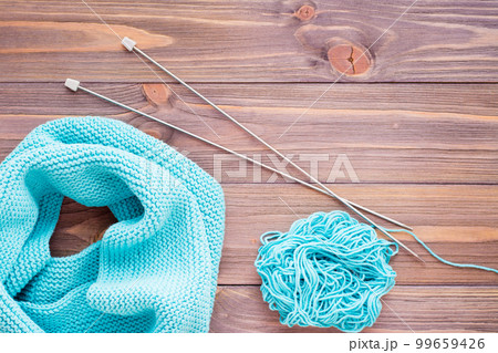 Knitted mint  snud, needles and  tangle on a wooden table. Top view 99659426