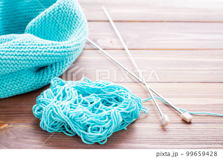 Knitted mint  snud, needles and  tangle on a wooden table 99659428