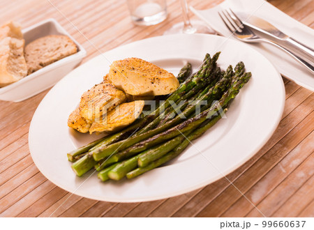 fried chicken breast pieces with asparagus on white plate 99660637