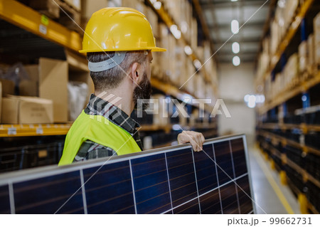 Rear view of warehouse worker carring solar panel. Rear view of warehouse worker carring solar panel. 99662731