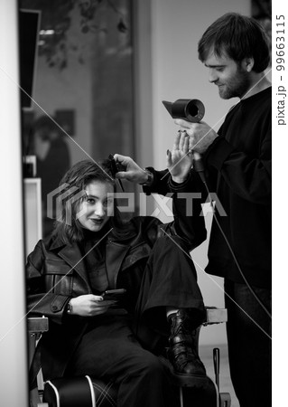 man hairdresser dries female hair with hairdryer after washing man hairdresser dries female hair with hairdryer after washing 99663115