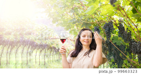 Beautiful woman dreaming tasting red wine enjoying summer stay in vineyards on lovely sunny day Beautiful woman dreaming tasting red wine enjoying summer stay in vineyards on lovely sunny day 99663323