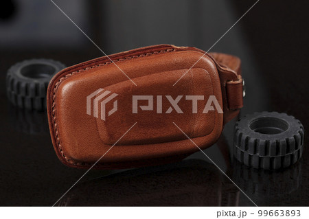 Leather case for car keys on a black background. 99663893