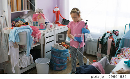 Little girl doing room cleaning with a broom at home. Concept of household chores and housework Little girl doing room cleaning with a broom at home. Concept of household chores and housework 99664685