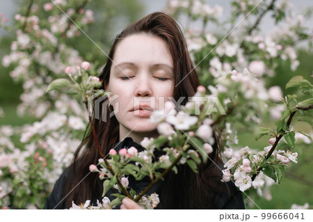 Woman with natural makeup, floral cosmetics for skin of the face, girl posing in flower branches of blooming apple tree in spring Woman with natural makeup, floral cosmetics for skin of the face, girl posing in flower branches of blooming apple tree in spring 99666041