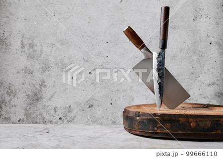 Knive and cleaver sticking out of wooden block 99666110