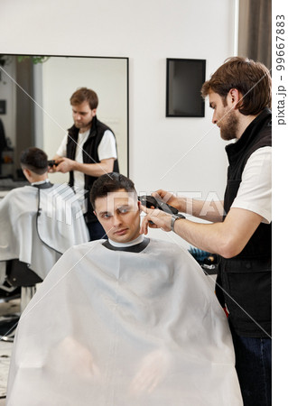 Barber shaving caucasian man in barber shop. Barber shaving caucasian man in barber shop. 99667883