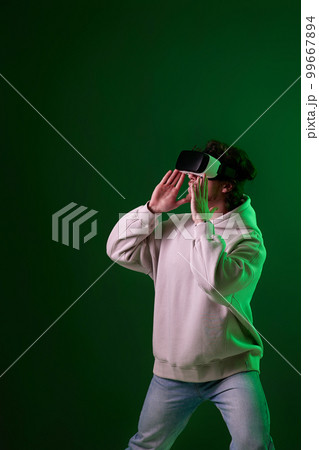 man in vr glasses and sweatshirt plays on blue background. man in vr glasses and sweatshirt plays on blue background. 99667894