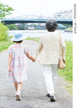 手をつないで歩く女の子とお婆ちゃん 手をつないで歩く女の子とお婆ちゃん 99668998