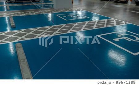 Car parking lot reserved for handicapped driver in supermarket or shopping mall. Car parking space for disabled people. Wheelchair sign paint on parking area. Blue and white handicapped parking lot. Car parking lot reserved for handicapped driver in supermarket or shopping mall. Car parking space for disabled people. Wheelchair sign paint on parking area. Blue and white handicapped parking lot. 99671389