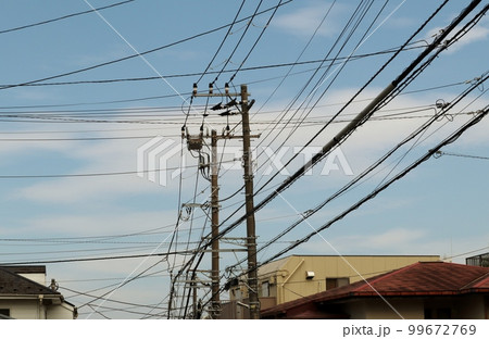 様々なケーブルや電線とそれらを支える電柱 99672769