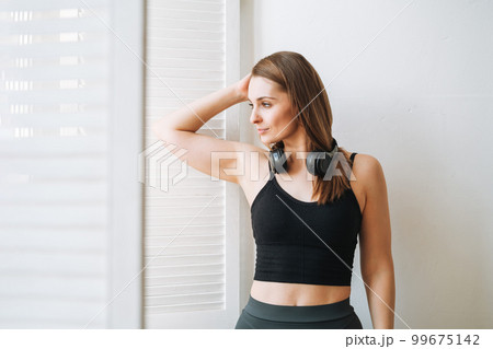 Young slim woman in sportwear and heapphones girl dancer at bright studio 99675142