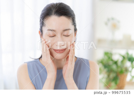 肌を触って微笑むミドルエイジの女性 99675535