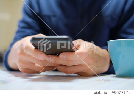 スマホを見ながらコーヒーを飲む男性 99677179