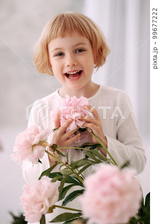 Girl 6-7 years old in a white dress holds a flower Girl 6-7 years old in a white dress holds a flower 99677222