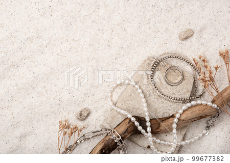 Beautiful Silver and Pearl Jewelry on white stones and sand. Various jewelry - bracelets, necklaces and rings. Place for text. Beautiful Silver and Pearl Jewelry on white stones and sand. Various jewelry - bracelets, necklaces and rings. Place for text. 99677382