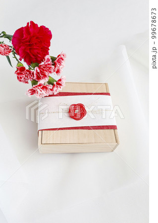 カーネーションの花束と和風ラッピングをしたプレゼント 99678673