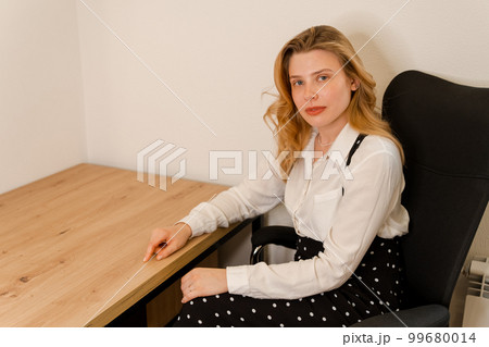 Attractive young confident businesswoman sitting at the office table. Attractive young confident businesswoman sitting at the office table. 99680014