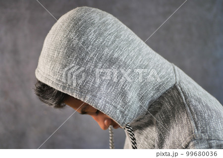 sad man in hood cover face with hands isolated in black. 99680036