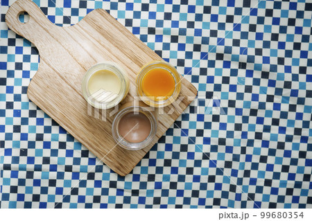 Caramel, chocolate and mango pudding in a glass jar on pink background  99680354