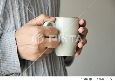 Close up of women's hand holding coffee mug Close up of women's hand holding coffee mug 99681115