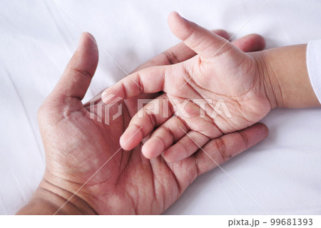 father holding hand of baby child, close up . 99681393