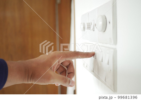 A finger turning on lighting switch . 99681396
