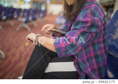 Woman waiting for departure at the airport on your vacation hold passport and smartphone while waiting boarding on departure area International Airport 99682175