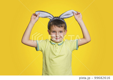 Little boy in t-shirt is touching his bunny ears and smiling Little boy in t-shirt is touching his bunny ears and smiling 99682616