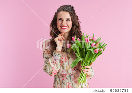 pensive stylish woman with long wavy brunette hair on pink 99683751