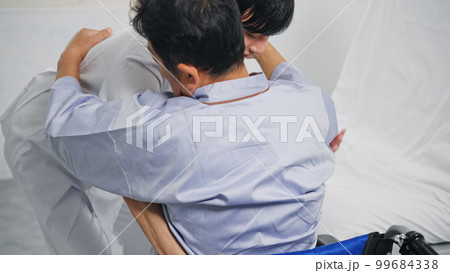 ベッドから車椅子へ移乗介助する介護士 99684338