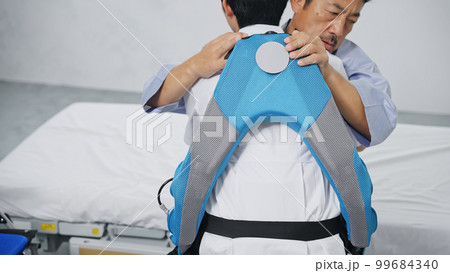 パワーアシストスーツをつけて患者を抱える看護師 移乗介助機器 パワーアシストスーツをつけて患者を抱える看護師 移乗介助機器 99684340