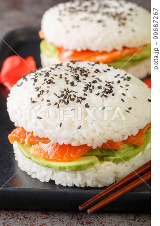Avocado and Salmon Sushi Burger with black sesame and ginger close-up on a plate. Vertical Avocado and Salmon Sushi Burger with black sesame and ginger close-up on a plate. Vertical 99687267