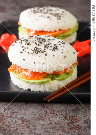 Sushi sandwich with rice, salmon, avocado and sesame close-up on a plate. Vertical 99687292