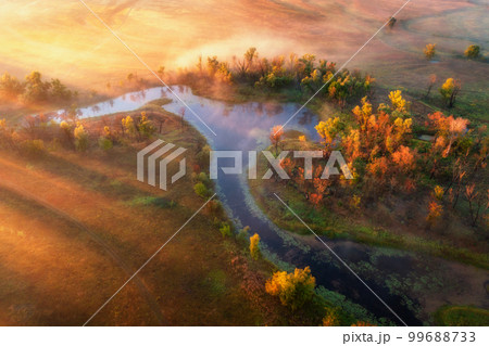 Aerial view of curving river in fog at sunrise in autumn Aerial view of curving river in fog at sunrise in autumn 99688733