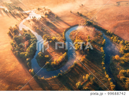 Aerial view of curving river in fog at sunrise in autumn Aerial view of curving river in fog at sunrise in autumn 99688742