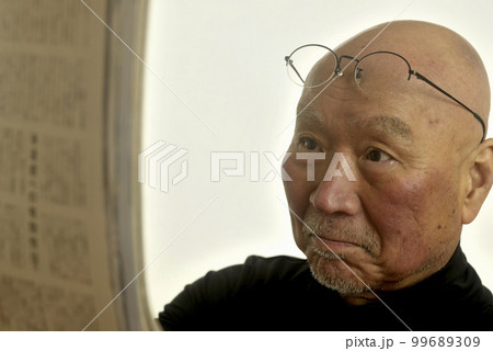 老眼のシニア男性が雑誌を読んでいる 99689309